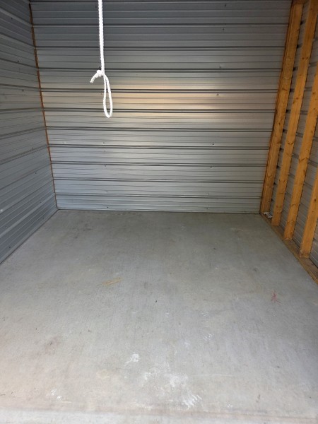 Clean interior of a storage unit showing metal corrugated walls and smooth concrete floor at U.S. 60 West Storage LLC