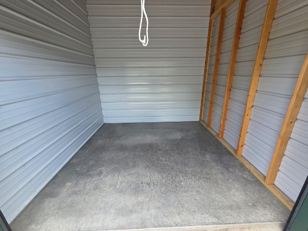 Interior view of a storage unit with metal walls and concrete floor, clean and ready for storage